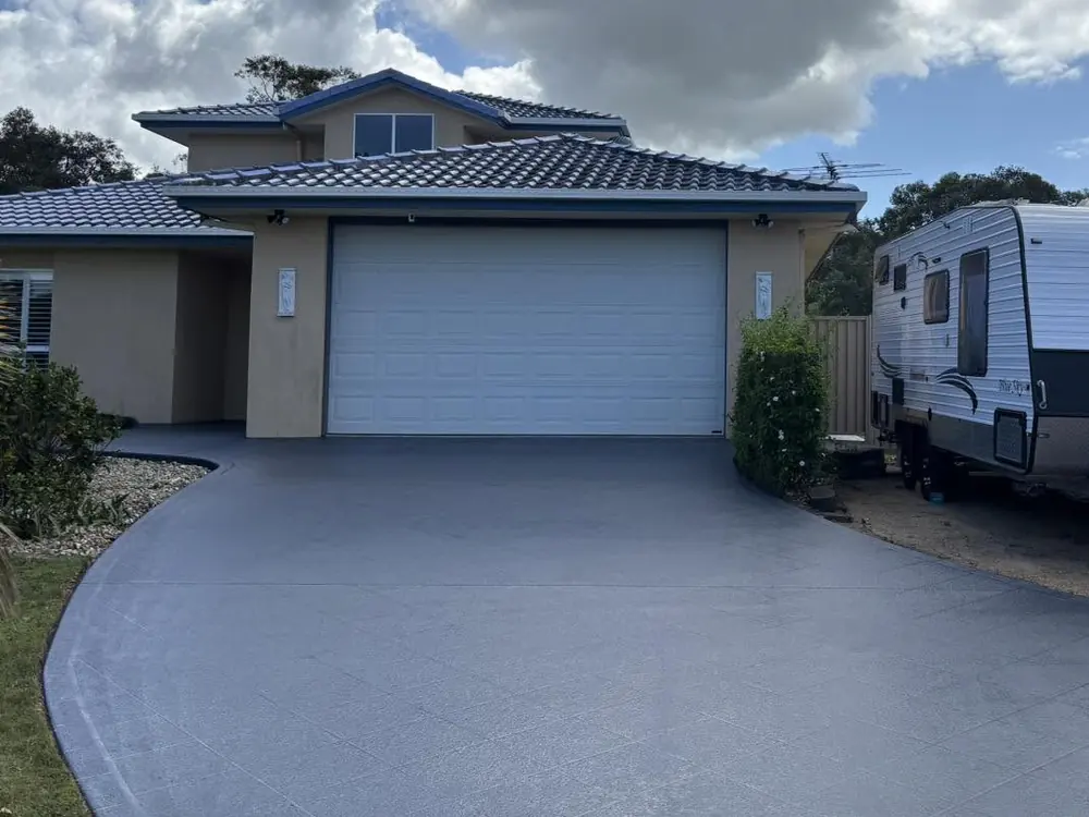 The same driveway after: re-coloured a deep blue-grey right up to the garage door, the stencil pattern still showing