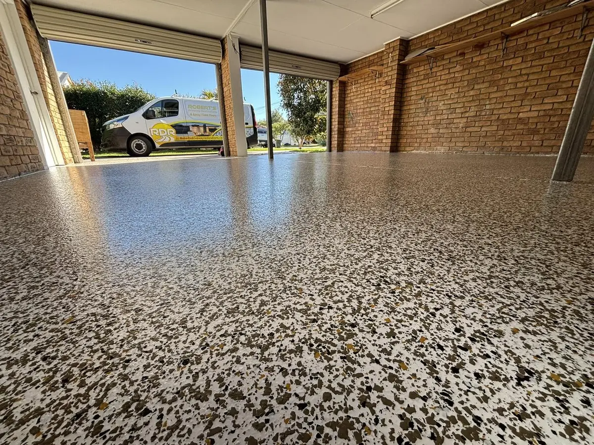 Carport floor in a cream, brown and gold epoxy flake, the signwritten RDR van parked on the driveway outside
