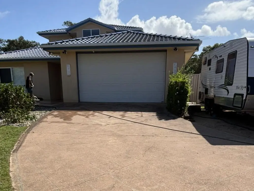 A stencilled driveway before, faded to a dusty pink in front of a double garage and a caravan
